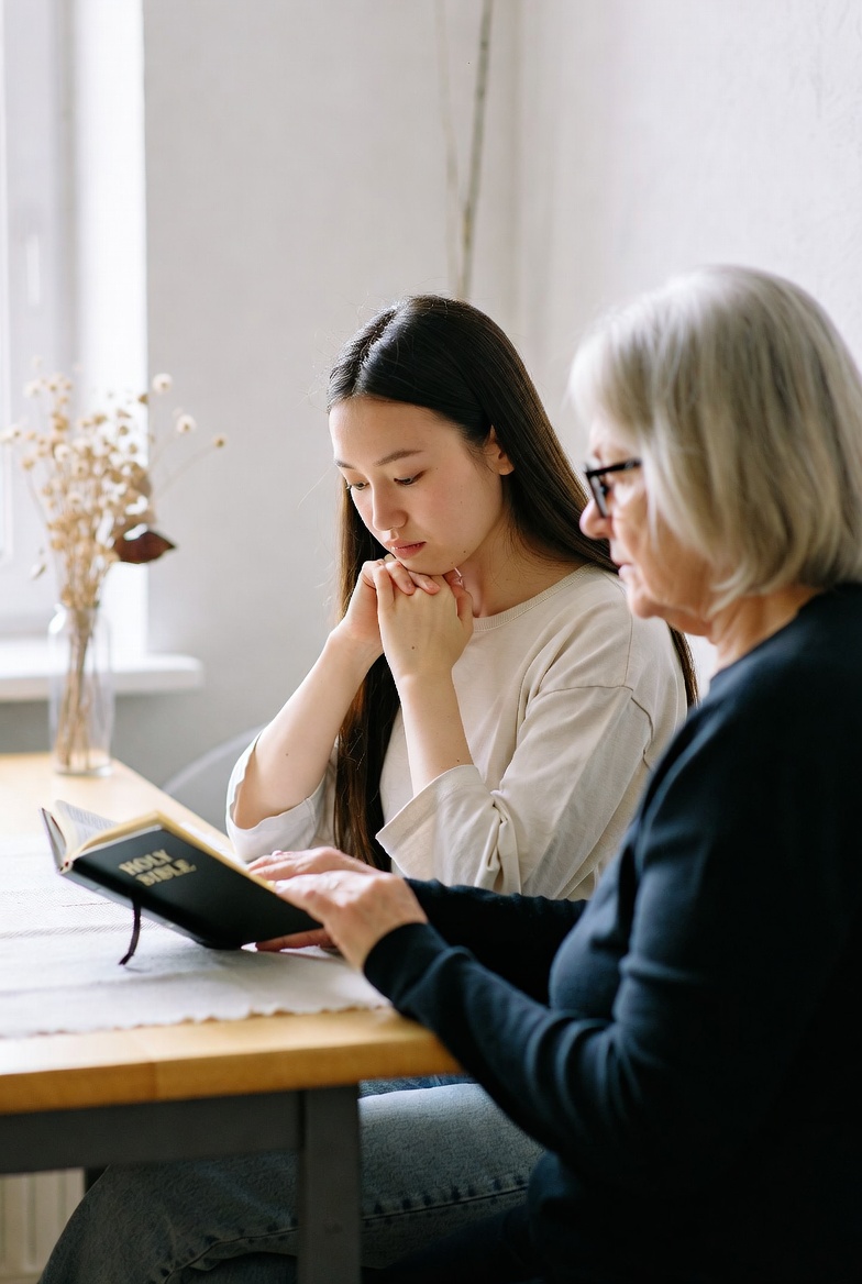 Young woman and older woman reading the Bible together